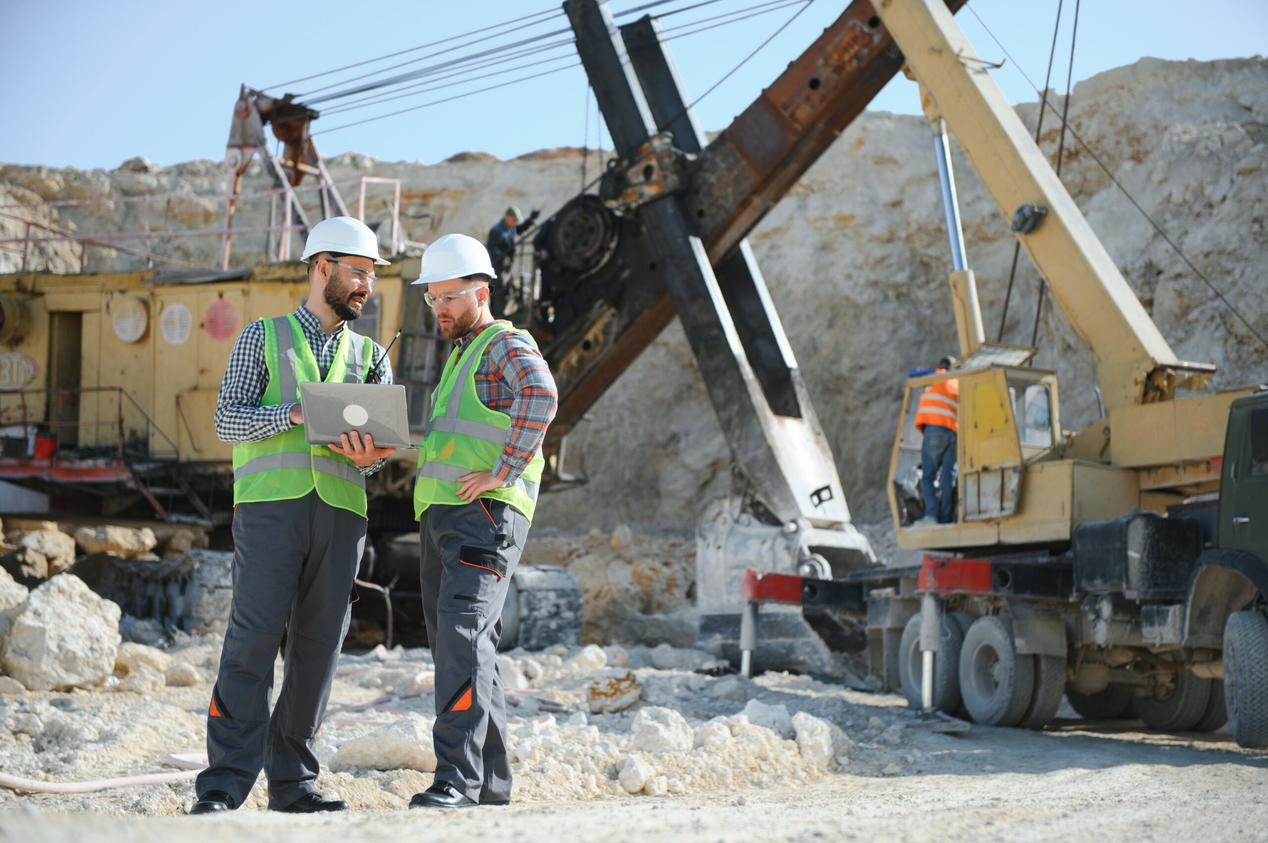 Portrait of stone quarry workers standing on the background of an excavator.